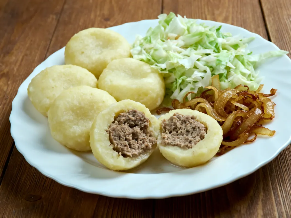 Pyzy z mięsnym nadzieniem podane z surówką i cebulką